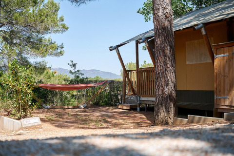 Safari tent Villatent Outback with a hammock at Camping Leï Suves, France, surrounded by trees in sunlight.