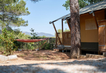 Safari tent Villatent Outback with a hammock at Camping Leï Suves, France, surrounded by trees in sunlight.