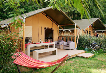 Tente safari Villatent Wood au Camping Domaine du Logis en France avec hamac et coin salon extérieur.