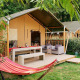 Tienda safari Villatent Wood en Camping Domaine du Logis en Francia con hamaca y zona de estar exterior.