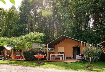 Safaritent Villatent Wood bij Camping Domaine du Logis in Frankrijk, omgeven door groene bomen en natuur.