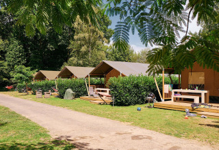 Safaritenten op Camping Domaine du Logis in Frankrijk, tussen groen en met houten terrassen om te relaxen.