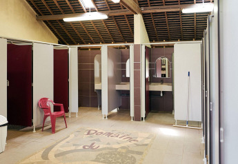 Servizi igienici puliti e spaziosi con cabine e lavandini al Camping Domaine du Logis in Francia.