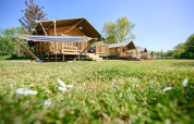Safari tents at Villatent Nomad, Holiday Resort de Bronzen Emmer, Netherlands, on a sunny green field.
