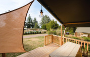 View from Villatent Outback lodge at Camping Le Sequoia in France, featuring wooden terrace and pool area.