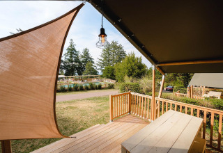 Uitzicht vanaf Villatent Outback bij Camping Le Sequoia in Frankrijk met houten terras en zwembadgedeelte.