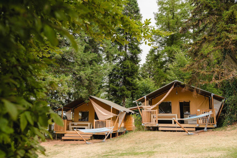 Twee gezellige lodges met veranda en hangmatten in het bos bij Villatent Outback, Camping Le Sequoia, Frankrijk.