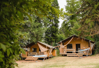 Dos cómodas cabañas con terrazas y hamacas en un bosque en Villatent Outback, Camping Le Sequoia, Francia.