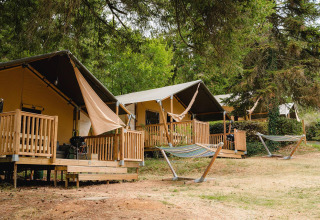 Villatent Outback op Camping Le Sequoia in Frankrijk, tentlodges met houten veranda en hangmatten buiten.