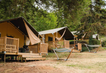 Villatent Outback op Camping Le Sequoia in Frankrijk, tentlodges met houten veranda en hangmatten buiten.