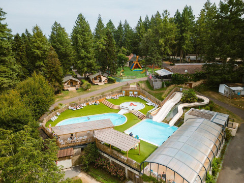 Vista aerea di Villatent Outback al Camping Le Sequoia in Francia, con piscine, scivoli e alberi attorno.