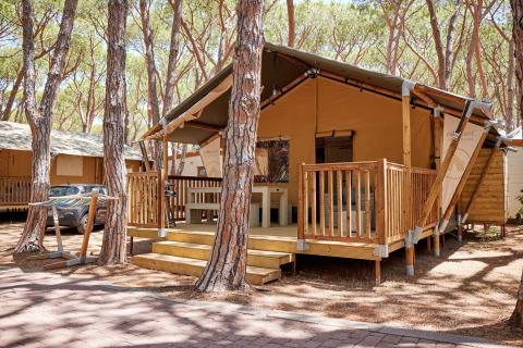 Villatent Outback lodge op Camping Village Baia Blu La Tortuga in Italië tussen de hoge dennebomen.