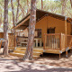 Lodge Villatent Outback en Camping Village Baia Blu La Tortuga, Italia, rodeado de altos pinos.