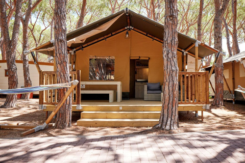 Villatent Outback al Camping Village Baia Blu La Tortuga in Italia, circondata da alti pini verdi.