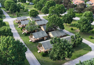 Luchtfoto van Villatent Outback lodge met ruime tenten, groene bomen en paden op het kampeerterrein.