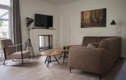 Moderne woonkamer in Veluwe Villa, De Boshoek, Nederland, met bruin bankstel en herten wanddecoratie.