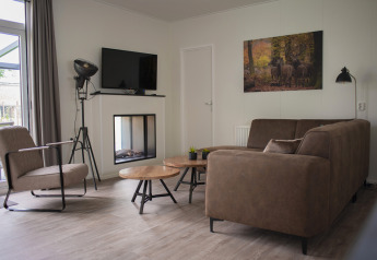 Sala moderna en Veluwe Villa, De Boshoek, Países Bajos, con sofá marrón y cuadro de ciervos en la pared.