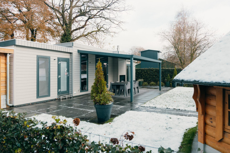 Veluwe Villa at Holiday park De Boshoek in the Netherlands with snow-covered lawn and modern patio