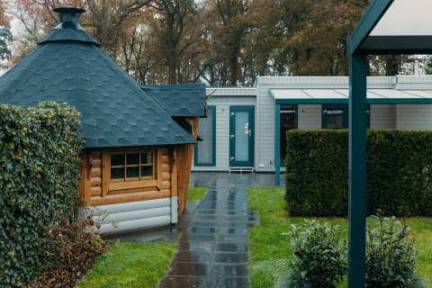Veluwe Villa lodge in vakantiepark De Boshoek in Nederland, met tuin en houten chalet zichtbaar.