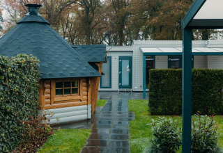 Veluwe Villa lodge in vakantiepark De Boshoek in Nederland, met tuin en houten chalet zichtbaar.