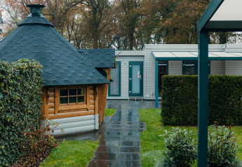 Veluwe Villa Lodge im Ferienpark De Boshoek, Niederlande, mit Holzhaus und gepflegtem Garten.
