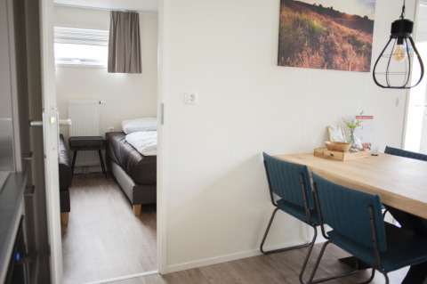 Vista interior del dormitorio y comedor con sillas azules en Veluwe Villa del parque De Boshoek, Países Bajos.