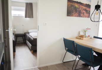 Vue intérieure de la chambre vers la salle à manger avec chaises bleues à Veluwe Villa, De Boshoek, Pays-Bas.