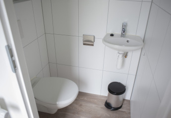 Moderne og kompakt badeværelse på Veluwe Villa, Holiday park De Boshoek, med toilet og håndvask.