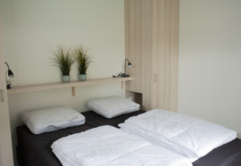 Dormitorio moderno de lodge en Veluwe Villa, Holiday park De Boshoek, Países Bajos, con dos camas y plantas.