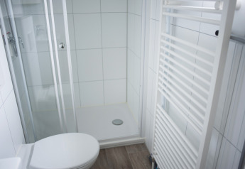 Baño moderno con ducha, inodoro y radiador toallero en Veluwe Villa, Holiday Park De Boshoek, Países Bajos.