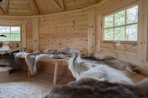 Binnenkant van een houten lodge met banken en vachten in Veluwe Villa, Holiday park De Boshoek, Nederland.