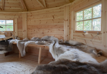 Interno di un lodge in legno con panchine e pelli presso Veluwe Villa, Holiday park De Boshoek, Paesi Bassi.