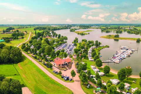 Luftfoto af Villa Maritiem med bådehavn, campingvogne og frodigt landskab ved søen på en solrig dag.