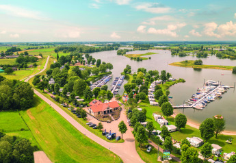 Foto aérea de Villa Maritiem con puerto deportivo, caravanas y entorno verde junto a un lago soleado.