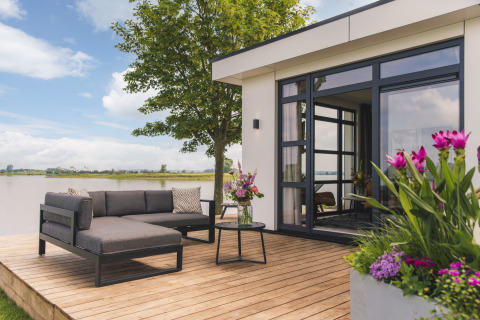 Moderne terrasse ved Villa Maritiem på MarinaPark Bad Nederrijn, med udsigt over vandet og blomsterdekorationer.