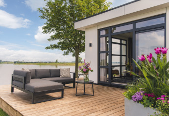 Moderne Terrasse der Villa Maritiem im MarinaPark Bad Nederrijn, Niederlande, mit Seeblick und Blumen.
