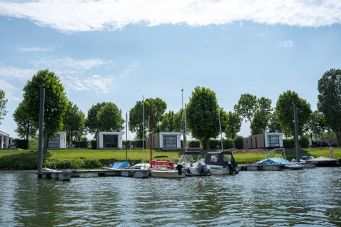 Udsigt over MarinaPark Bad Nederrijn med bådebro, små både og moderne Villa Maritiem lodges i Holland.