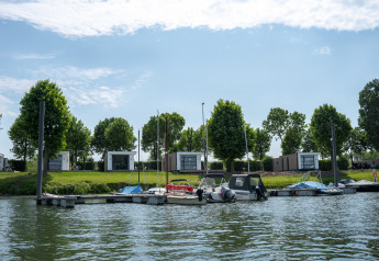 Vista de MarinaPark Bad Nederrijn con embarcadero, barcos pequeños y modernas villas Maritiem en Países Bajos.