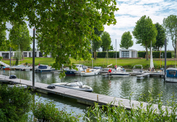 Boats docked at the marina near Villa Maritiem at MarinaPark Bad Nederrijn in the Netherlands, trees nearby.