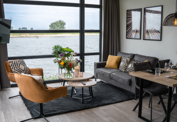 Salón moderno en Villa Maritiem con grandes ventanales, vista al río y elegante decoración interior.