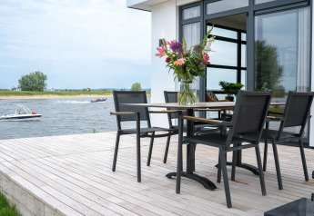 Terraza en Villa Maritiem, MarinaPark Bad Nederrijn, Países Bajos, con mesa, sillas y vista al río.