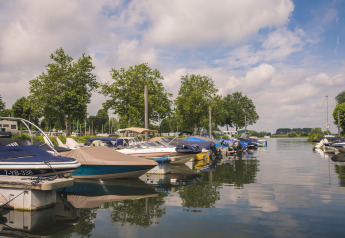 Barcos atracados en Villa Maritiem en MarinaPark Bad Nederrijn, Países Bajos, día soleado y tranquilo.