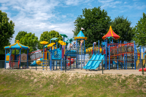 Parque infantil colorido en Villa Maritiem con toboganes, columpios y niños disfrutando al aire libre.