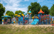 Kleurrijke speeltuin bij Villa Maritiem met glijbanen, klimrekken en kinderen spelend in de buitenlucht.