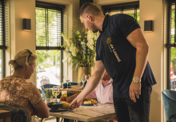 A waiter serves food to two guests at Villa Maritiem’s restaurant in MarinaPark Bad Nederrijn, Netherlands.
