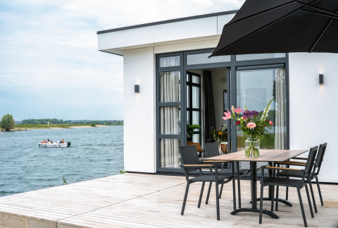 Lodge moderno sul lungolago con terrazza, tavolo con fiori e vista barca a Villa Maritiem, MarinaPark Bad Nederrijn.