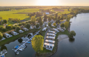 Vista aérea de Villa Maritiem en MarinaPark Bad Nederrijn, Países Bajos, cabañas junto al lago con campo verde.