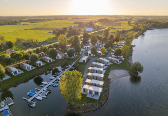 Luftfoto af Villa Maritiem ved MarinaPark Bad Nederrijn, Holland, med hytter ved søen og grønne marker.