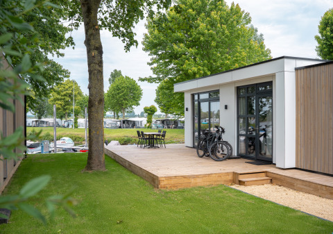Lodge moderno con terrazza in legno, biciclette e tavolo esterno a Villa Maritiem, MarinaPark Bad Nederrijn, Paesi Bassi.