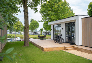 Lodge moderno con terraza de madera, bicicletas y muebles exteriores en Villa Maritiem, MarinaPark Bad Nederrijn, Países Bajos.